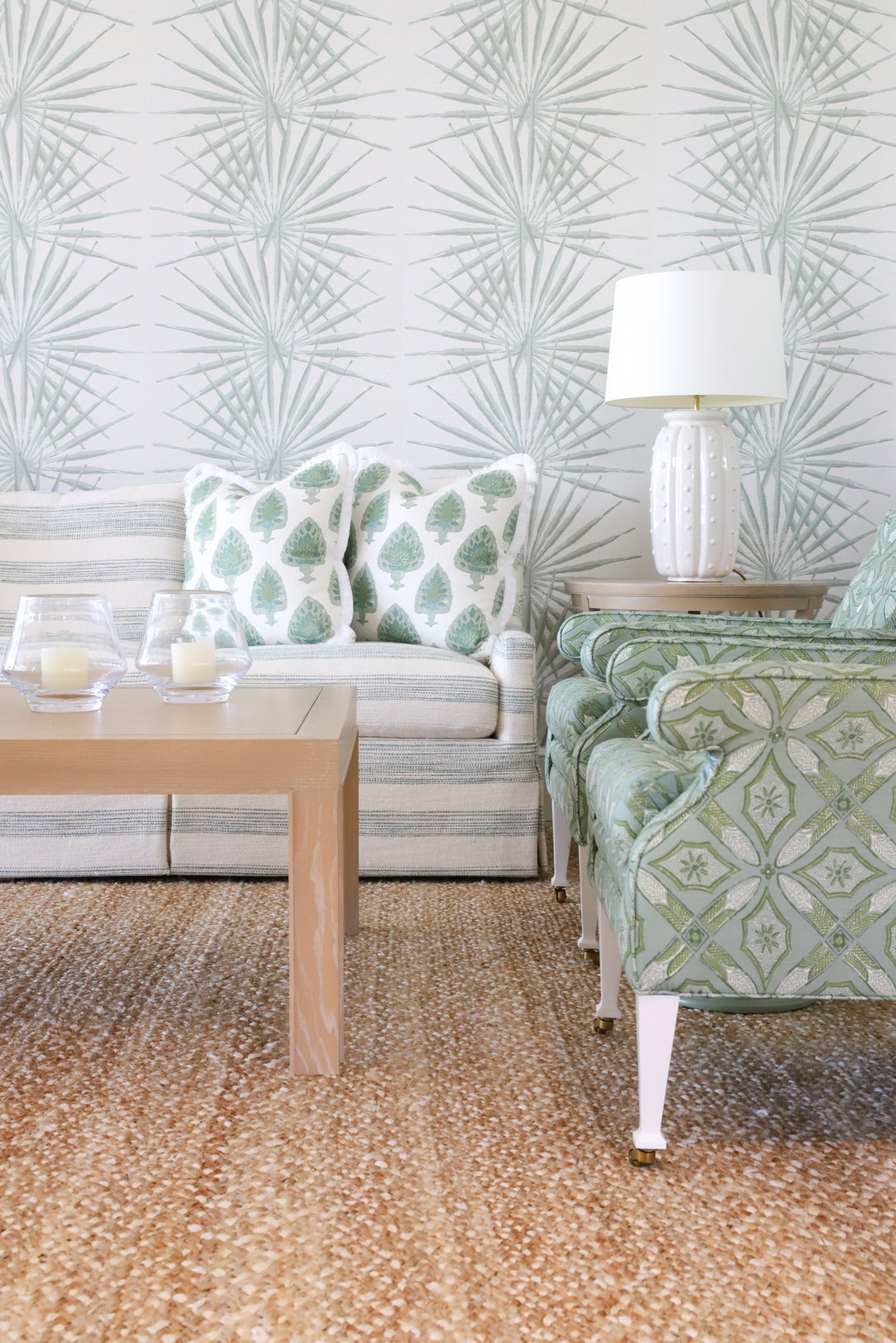 Living room with seafoam chairs, wallpaper, and sofa, with natural woven rug