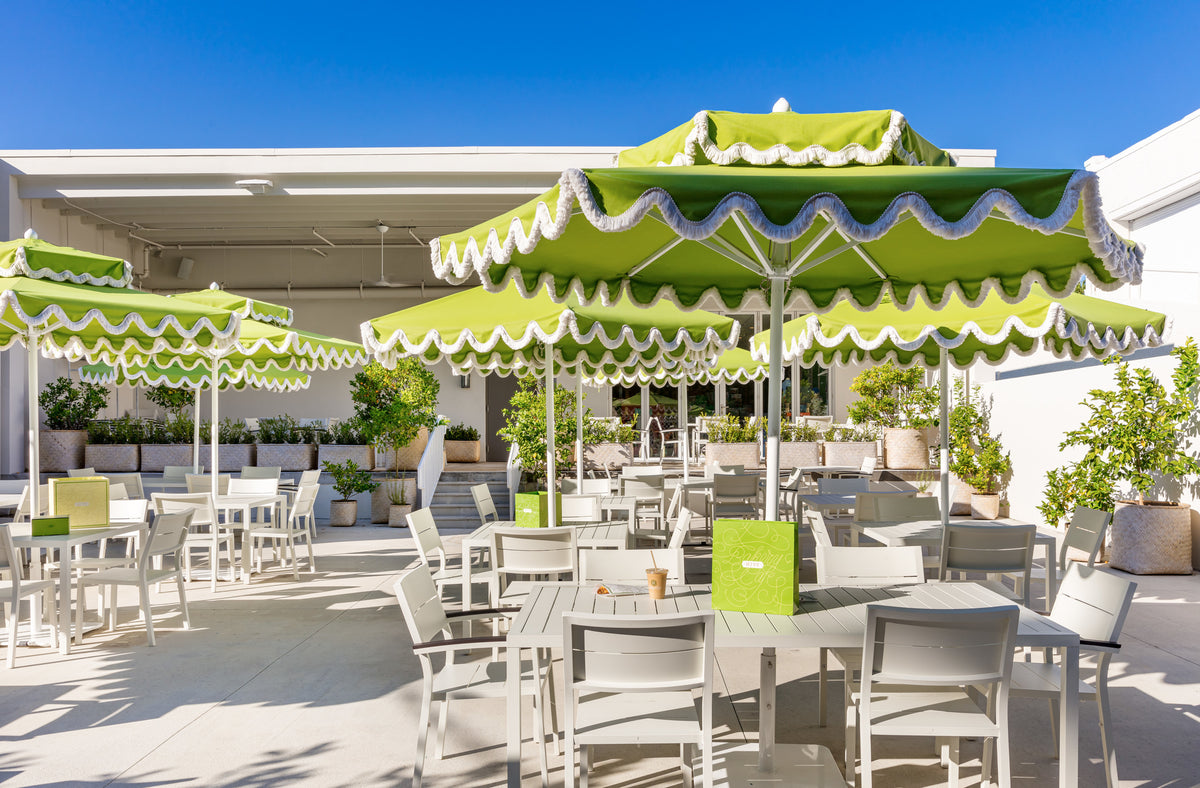 Outdoor dining at hive with white tables and green umbrellas