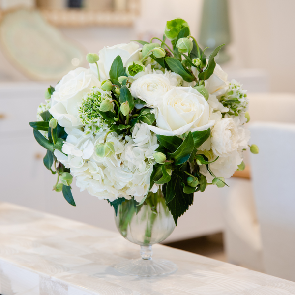 A versatile choice of Live Classic Floral Arrangements, featuring a bouquet of white flowers in an April Vase on a table by Hive Floral Studio.