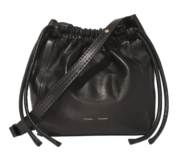 The Proenza Schouler Drawstring Pouch is a black leather shoulder bag with a sleek finish, featuring the brand name "Proenza Schouler" embossed in gold foil at the bottom.