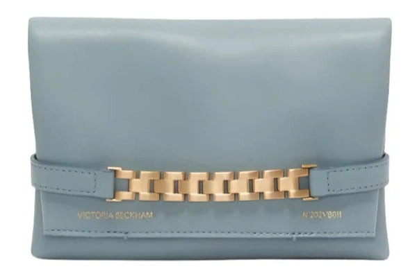 A Victoria Beckham Chain Pouch Mini in light blue with a gold-tone chain detail accent and "Victoria Beckham" inscribed near the bottom.