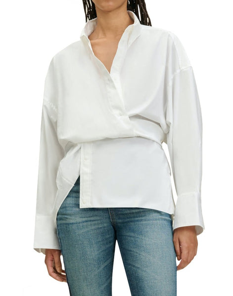 A person wears a white Dorothee Schumacher Poplin Power Wrap Blouse, partially tucked into blue jeans, supporting the Better Cotton Initiative.