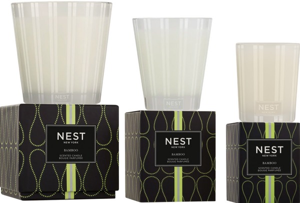 Two NEST Bamboo Candle Collection candles in frosted glass holders are displayed on top of their black and green Nest packaging, labeled "Bamboo Scented Candle" by Nest.