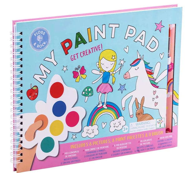 A children's paint pad titled "Floss & Rock My Painting Pad, Rainbow Fairy" by Floss and Rock features a fairy and whimsical illustrations on the cover. It includes pictures, 8 eco-friendly paint palettes, and a brush.