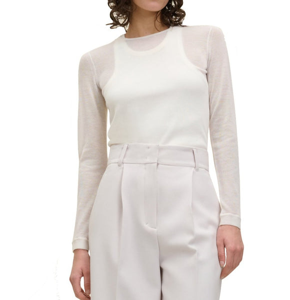 A person wearing the Dorothee Schumacher Bodycon Luxury O-Neck Sweater paired with high-waisted, pleated, light-colored pants. The photo is cropped at the shoulder and waist, highlighting their elegant yet understated style reminiscent of a luxury cashmere ensemble.