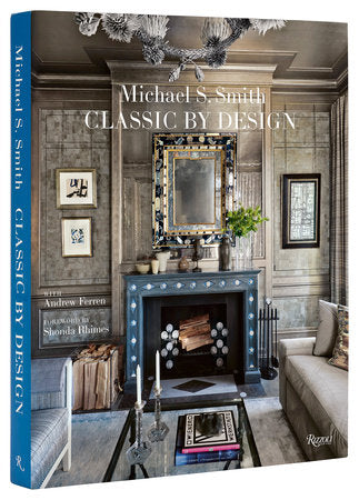 The book cover of "Classic by Design" from Rizzoli, authored by Michael S. Smith, highlights his exceptional design skills with an interior featuring a fireplace, mirror, and artwork on a wooden wall.