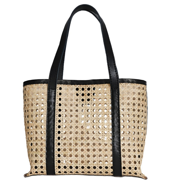 The Bembien Margot Bag, Mini by Bembien is a beige rattan cane tote handwoven in Bali, featuring black leather straps and trim with a perforated design.