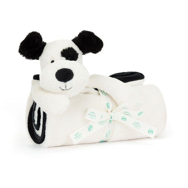 A Jellycat Bashful Black & Cream Puppy Blankie, this plush toy dog has soft fur and holds a rolled white blanket tied with a white ribbon featuring green text.