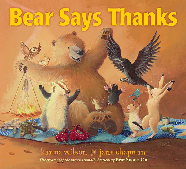 Illustrated cover of Simon & Schuster's playful picture book "Bear Says Thanks" by Karma Wilson and Jane Chapman, featuring a bear throwing a feast with various animal friends having a picnic on a blanket.