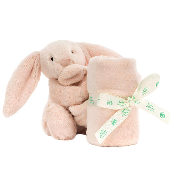 Presenting the Jellycat Bashful Blush Bunny Soother, a delightful plush companion from Jellycat. This charming bunny cuddles a rolled beige blanket secured with a ribbon, crafted from recycled fibers for an eco-friendly touch.