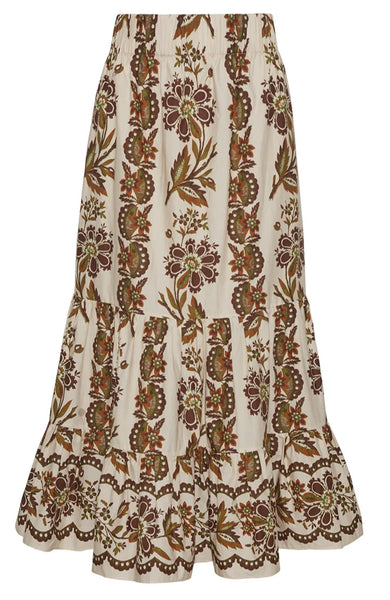 The Cara Cara Chase Skirt by Cara Cara is a knee-length, double tiered midi skirt with an elastic waistband, showcasing a floral and leaf pattern in brown, green, and reddish hues on a cream background.