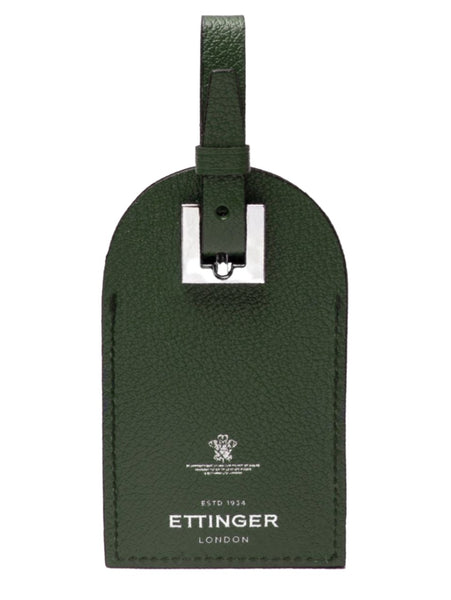 The Ettinger Capra Luggage Tag with Security Flap, crafted in green goat leather, boasts a strap with a silver buckle and an embossed "Ettinger London, Estd 1934" logo accompanied by a crest, emphasizing its durability.