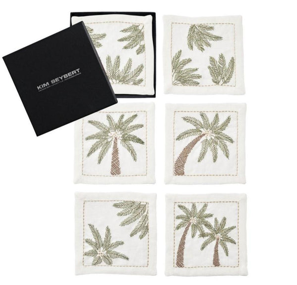 A set of six white fabric napkins adorned with embroidered palm leaf designs, perfect for adding a tropical touch. Accompanied by a sleek black box featuring "Kim Seybert," these Palm Coast Cocktail Napkins are an elegant addition to any gathering.