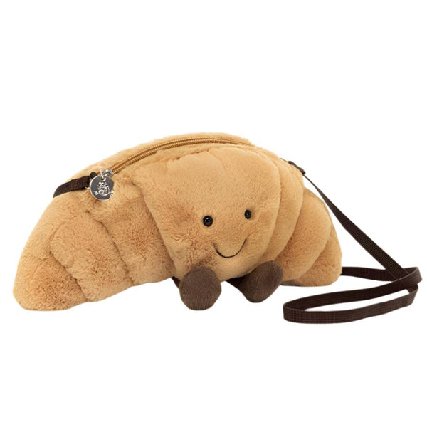 Immerse yourself in the allure of cafe culture with the Jellycat Amuseables Croissant Bag. This adorable croissant-shaped accessory by Jellycat showcases a charming smiling face, brown legs, and a handy zipper on top. Its adjustable cross-body strap makes it an ideal choice for carrying your essentials in style.