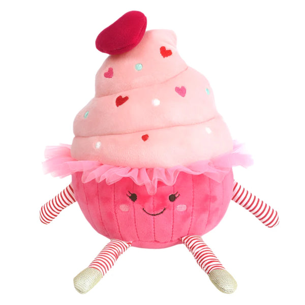 The MON AMI Candy Cupcake by Mon Ami is a snuggable plush featuring a pink frosting top adorned with hearts, a red beret, rosy cheeks, a smiling face, and striped legs. It's perfect as a birthday gift for any age!