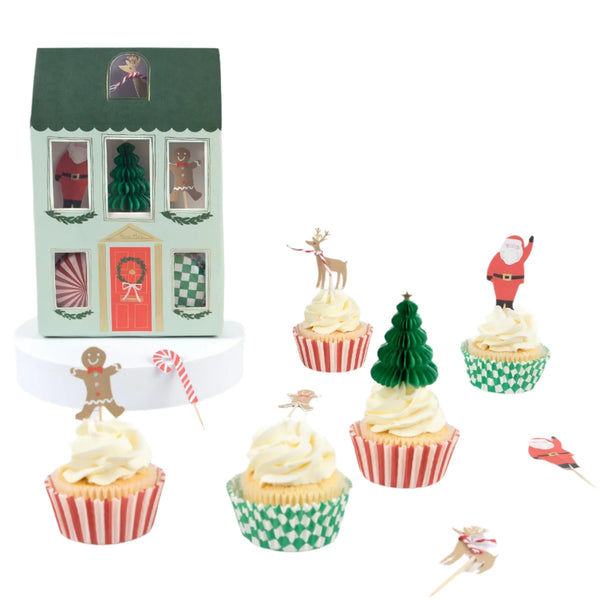 Meri Meri's Festive House Cupcake Kit, complete with 24 Christmas-themed toppers, is beautifully displayed beside a charming house-shaped box, highlighting the delightful Christmas cupcakes.