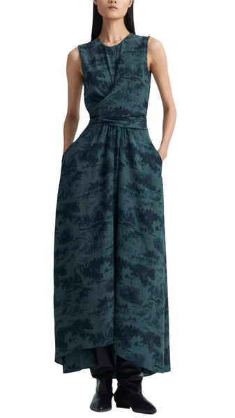 A person is wearing the Altuzarra Penny Dress, a sleeveless, ankle-length silk garment by Altuzarra featuring a striking dark green and black abstract pattern. The dress has a fitted top that transitions into a flared bottom, and is paired elegantly with black footwear.