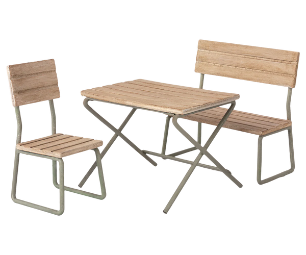 The **Maileg Garden Set, Miniature** by **Maileg** features a vintage design with a wooden table, bench, and chair all supported by metal frames. This elegant patio furniture set is perfect for enhancing any outdoor space and is made from FSC wood.