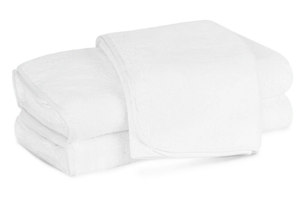 Two neatly folded bath towels from the Matouk Giza Bath Collection in white, crafted from plush Egyptian cotton, are stacked on top of each other against a plain background.