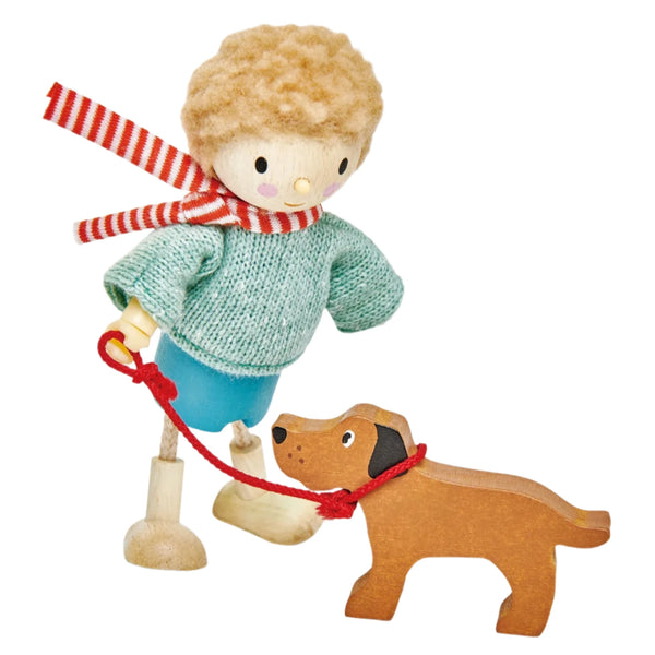 Introducing the "Tender Leaf Mr. Goodwood and his Dog" figurine by Tender Leaf Toys, featuring a child with curly hair, dressed in a quality blue outfit and wrapped in a striped scarf. The child holds a red leash attached to a dog exquisitely crafted from solid wood.