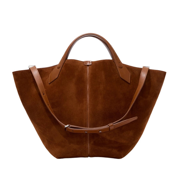 The Proenza Schouler Chelsea Large Soft Suede Tote is crafted from soft suede and features a wide base, short handles, and an adjustable shoulder strap.