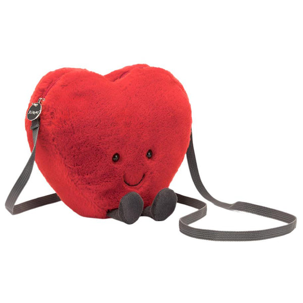 The Jellycat Amuseables Heart Bag is a charming plush heart-shaped cross-body bag by Jellycat, complete with a smiling face and feet, and featuring a black strap—making it the perfect Valentine's gift.