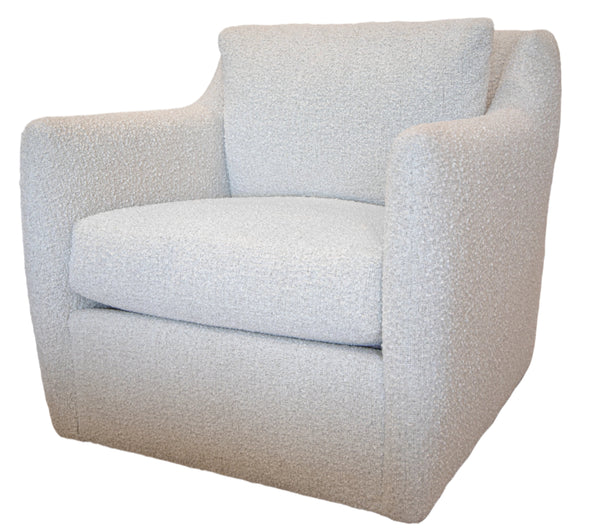 A light-colored, textured Swivel Chair upholstered in Village Linen fabric from Lee Industries, featuring a high back and armrests, placed on a rug in a well-lit room with wooden and wicker furniture in the background.