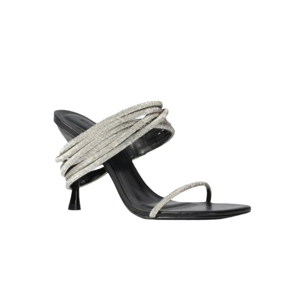 The Simkhai Infinity Crystal Strap Siren Sandal is an elegant black heeled sandal adorned with multiple metallic silver straps that wrap gracefully around the foot and ankle, making it perfect for evening wear. This model from Simkhai features a pointed toe, stiletto heel, and shimmering crystal accents that elevate its sophistication.