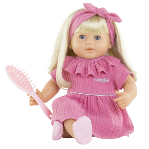 The Corolle Jade Baby Doll is a charming creation from the Corolle brand, featuring blonde hair and dressed in a lovely pink dress with a matching headband, ideal for hairstyling fun. Her vanilla-scented vinyl skin pairs perfectly with the pink brush she holds.