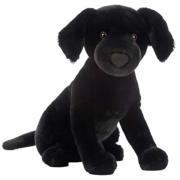 The Jellycat Pippa Black Labrador, a soft and plush black toy dog with floppy ears and a snuggly nose, sits upright against a white background, perfectly resembling a charming Black Labrador from the Jellycat brand.