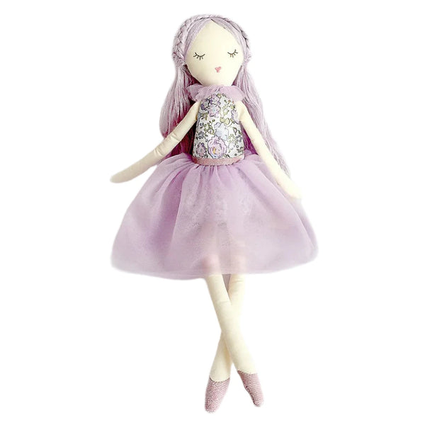 The MON AMI Lavender Scented Doll by Mon Ami is depicted against a plain white background. This charming doll features long purple hair, a lavender dress, and pink ballet shoes. Known for its calming effects, it's perfect for creating a soothing atmosphere.