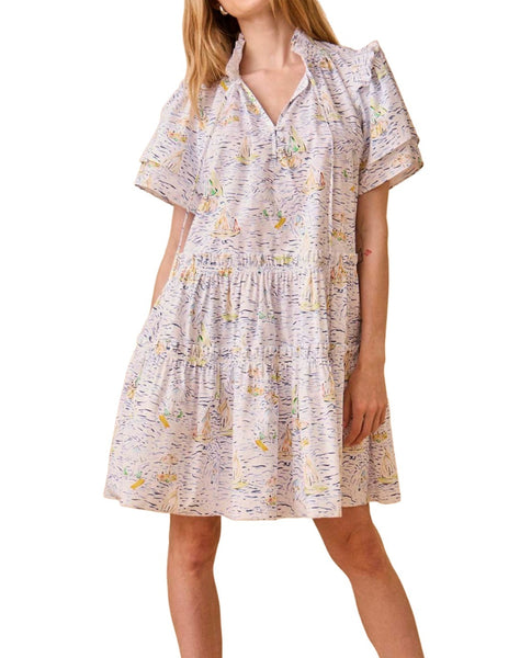 A woman wearing the Hunter Bell NYC Merritt Dress in lightweight cotton poplin, adorned with a regatta print of small boats. Her hands are in her pockets.