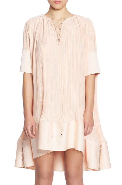 A person is wearing a Lanvin Short Sleeve Cascade Dress with a lace-up neckline and asymmetrical hem detailing, creating a subtle cascade effect.