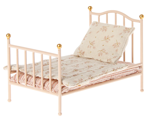 The Maileg Vintage Bed, Mouse - Rose provides a cozy spot for Maileg friends with its small size, pastel color, vintage metal frame featuring gold-tipped posts, complemented by floral bedding and a coordinating pillow.