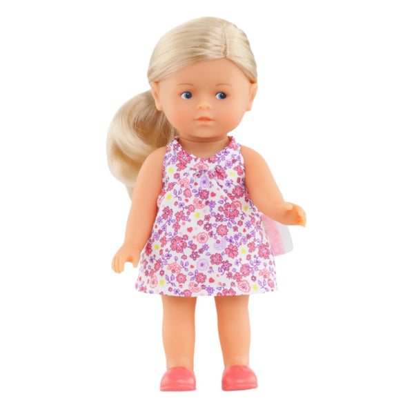 Brandishing a vinyl form, the Corolle Mini Corolline Doll is attired in a charming floral-print dress paired with pink shoes, artfully set against a pristine white background.