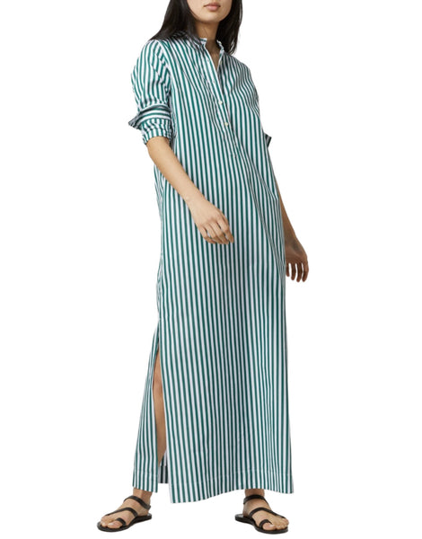 A person wearing the Ann Mashburn Mandarin Talitha Shirtdress, a long green and white vertically striped shirtdress with a mandarin collar, rolled-up sleeves, and side slits, paired with black sandals.