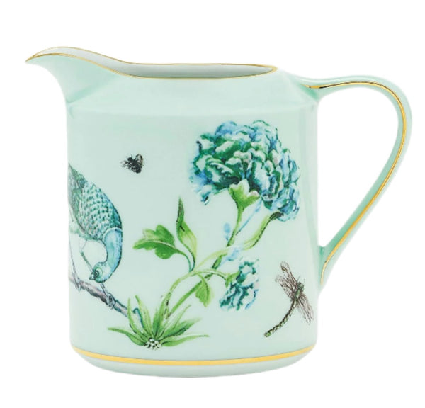 The Aquazzura Secret Garden Creamer, a kelly green floral ceramic jug from Aquazzura Casa, is adorned with illustrations of a bird, a flower, a dragonfly, and a bee. It boasts gold accents along the rim and handle, exuding an enchanting charm perfect for any table setting.