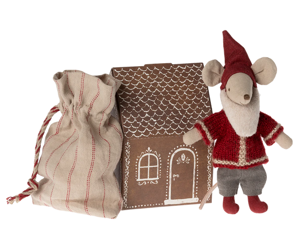 The Maileg Santa Mouse, dressed in festive attire, stands next to a drawstring bag and an enchanting cardboard gingerbread house, perfectly capturing the magic of Christmas night.