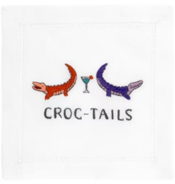 A set of August Morgan Cocktail Napkins Croc-Tails, featuring two stylized crocodiles, one red and one purple, with a cocktail glass between them, and the pun "croc-tails" written