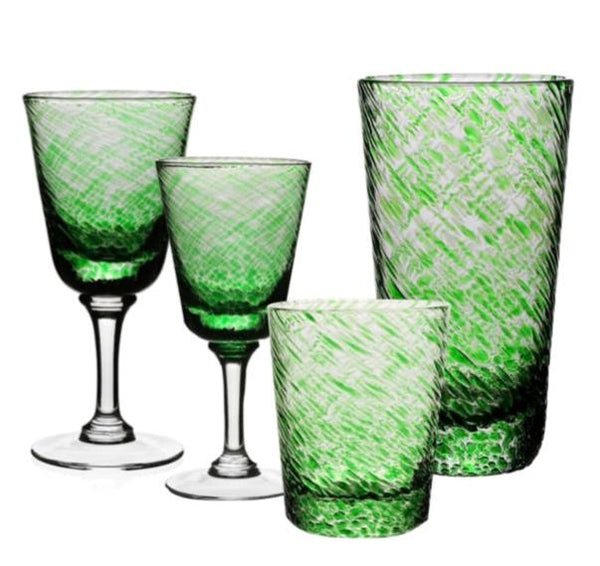 A set of green and transparent drinking glasses from the William Yeoward Crystal Vanessa Green Collection, featuring two wine glasses and two tumblers with a textured design that creates a subtle optical illusion.