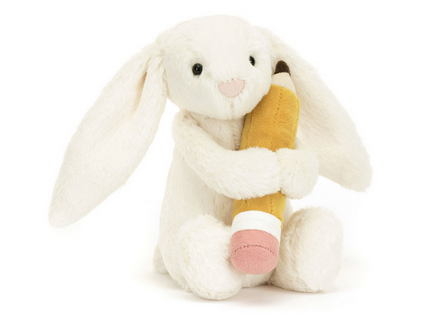 A Jellycat Bashful Bunny with Pencil plush white rabbit sits upright, holding a yellow pencil-shaped stuffed toy, making it the perfect calming study buddy during exam time.