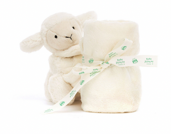 A Jellycat Bashful Lamb Soother toy sits next to a rolled-up, cream-colored baby blanket tied with a white ribbon labeled "Baby Jellycat," making it a perfect newborn gift.