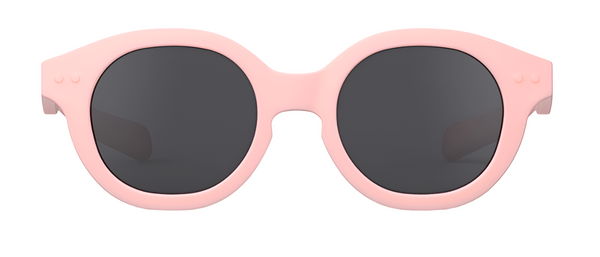 The IZIPIZI #C Polarized Sunglasses by IZIPIZI are a chic pair of round kids sunglasses featuring polarized black lenses and a light pink frame, ensuring both style and UV protection.