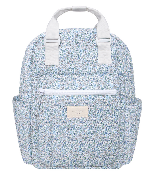 The Minnow Everyday Backpack by Minnow is a white quilted backpack adorned with a floral pattern, and it features two handles, adjustable padded shoulder straps, a front zipper pocket, and side pockets.