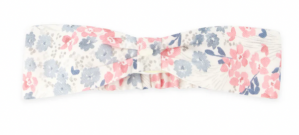 The Tartine et Chocolat Raspberry Printed Flowery Headband, a charming floral accessory from Tartine et Chocolat, showcases a delightful pattern of blue and pink flowers on a white background and is elegantly tied in a bow shape at the center to elevate your style.