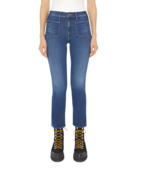 A person wearing the Mother Denim Patch Pocket Insider Flood jeans by Mother in mid-blue wash with front patch pockets, a white top, and black lace-up boots with yellow laces.