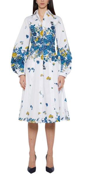 A person wearing a Prabal Gurung Long Sleeve Band Collar Shirtdress with blue and yellow patterns stands facing forward. The midi-length design reveals only the lower half of their legs and shoes.