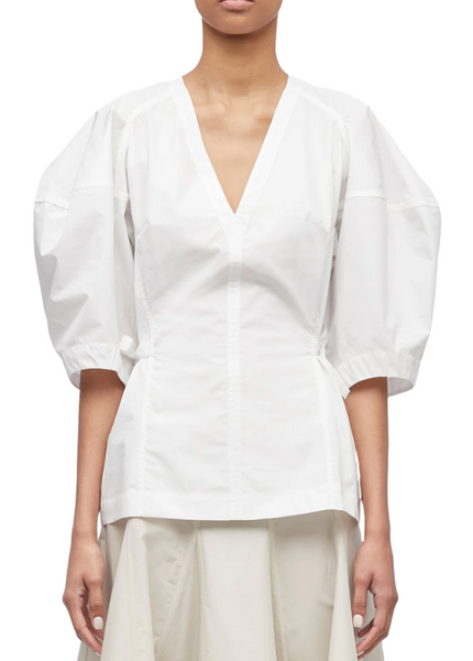 A person wearing a 3.1 Phillip Lim V Neck Puff Sleeve Top in white and a light-colored skirt stands against a plain background.