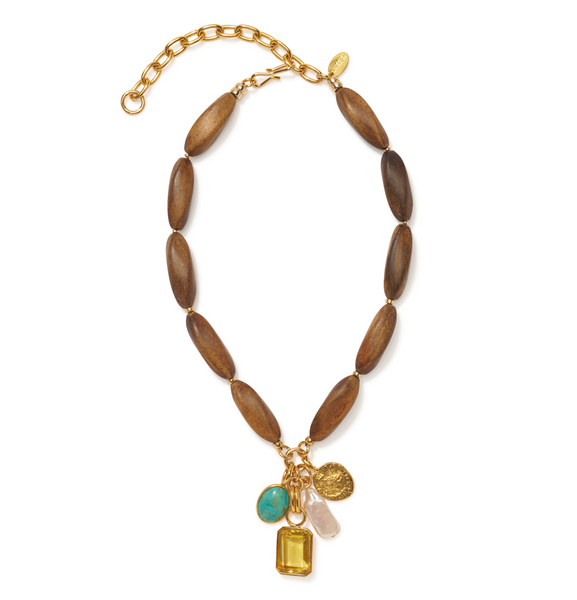 Introducing the Lizzie Fortunato Marilla Necklace by Lizzie Fortunato, featuring large wooden beads, an adjustable gold chain, and a variety of unique pendants including a turquoise stone, a 24-karat gold-plated brass rectangle, a pink crystal, and a gold medallion.