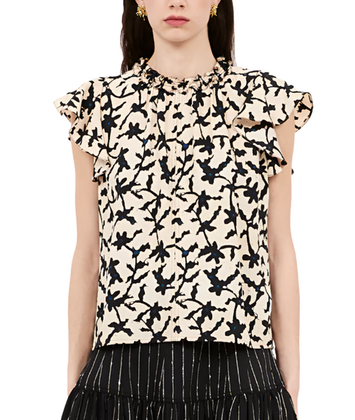 A person wearing an Ulla Johnson Julia Top, a cream-colored cap sleeve blouse with ruffles and a black floral pattern. The luxurious satin-back crepe top is paired with a black skirt featuring vertical white stripes.